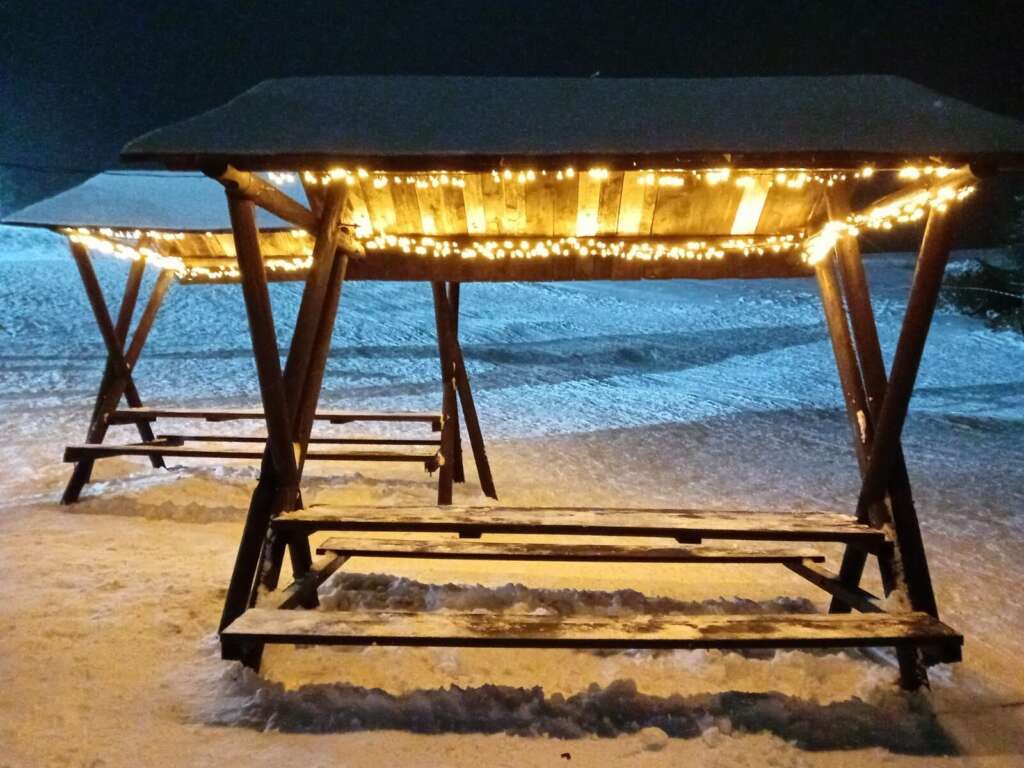 Überdachter Sitzplatz mit Lichterkette im Schnee