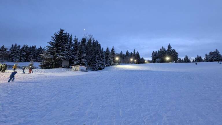 Skifahrer am Rotterhang in der Abenddämmerung, die Flutlichter sind eingeschaltet